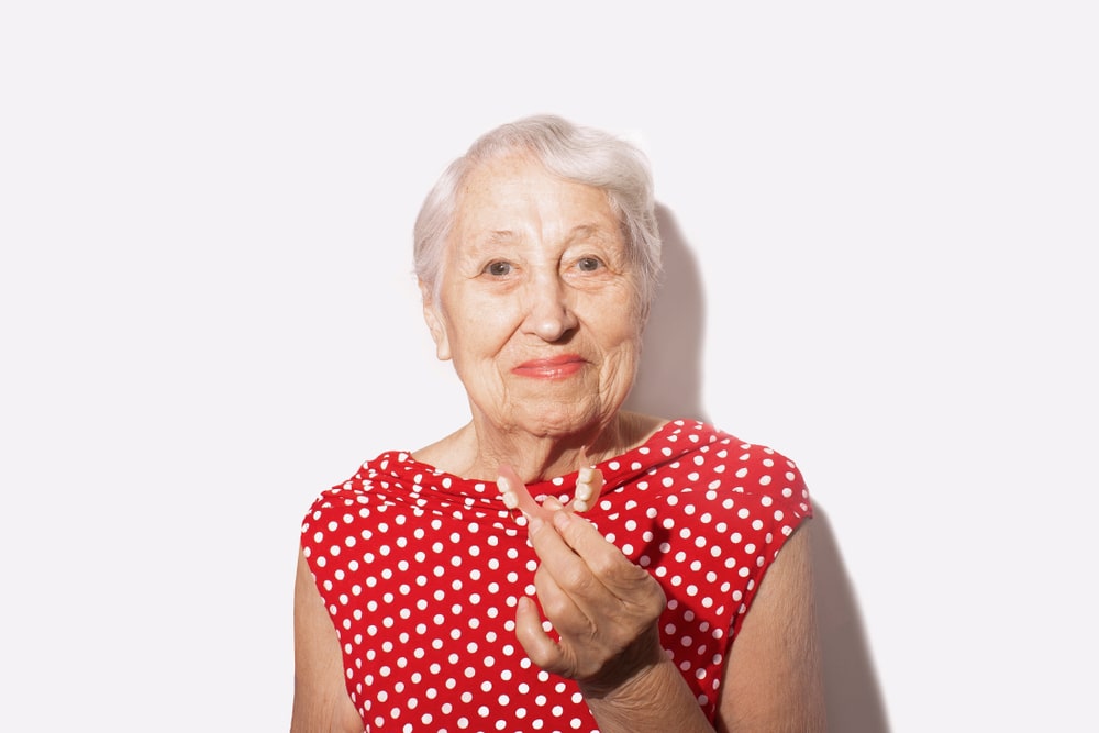 signora anziana mostra una protesi dentale mobile in nylon