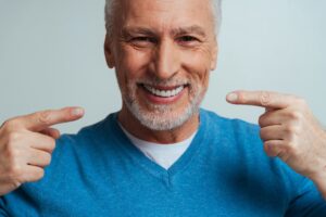 uomo adulto sorride mostrando denti e gengive dopo un trattamento laser per la cura della parodontite