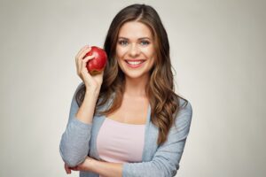 ragazza sorride mostrando una mela rossa in mano