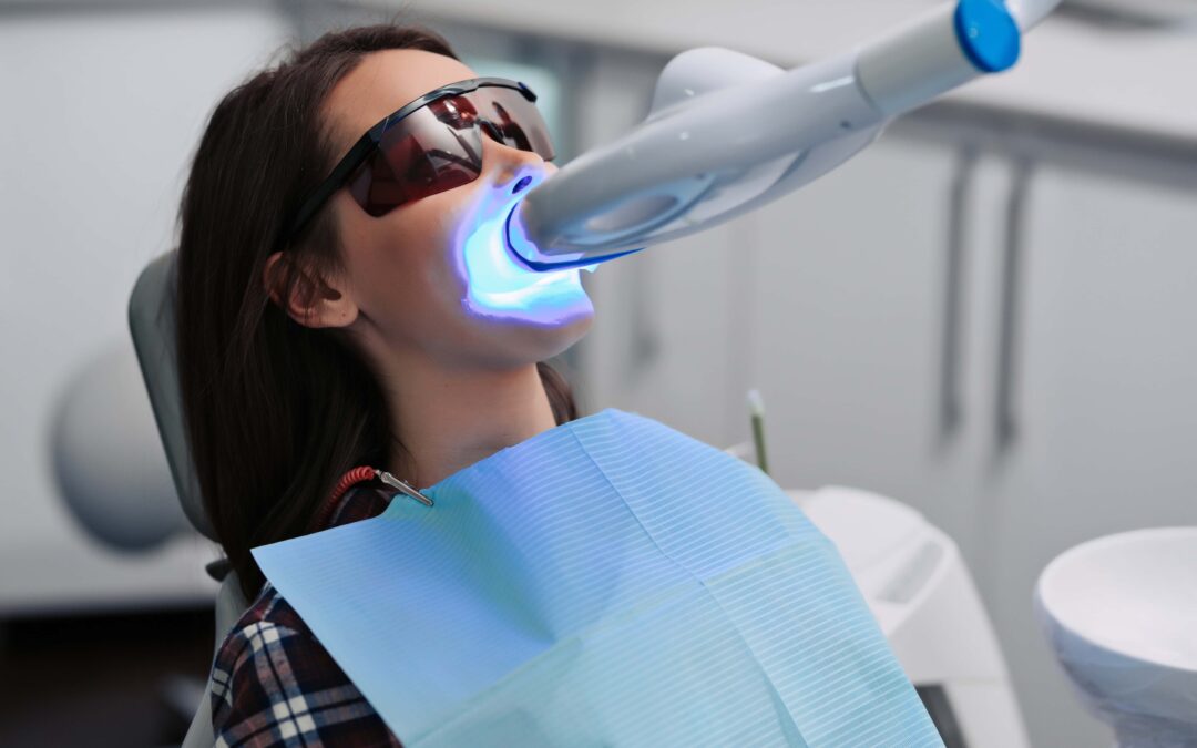 donna effettua seduta di sbiancamento dentale al led su poltrona del dentista