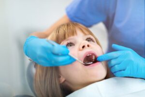 Dentista controlla la bocca. i denti di una bambina piccola sdraiata sul lettino dello studio dentistico